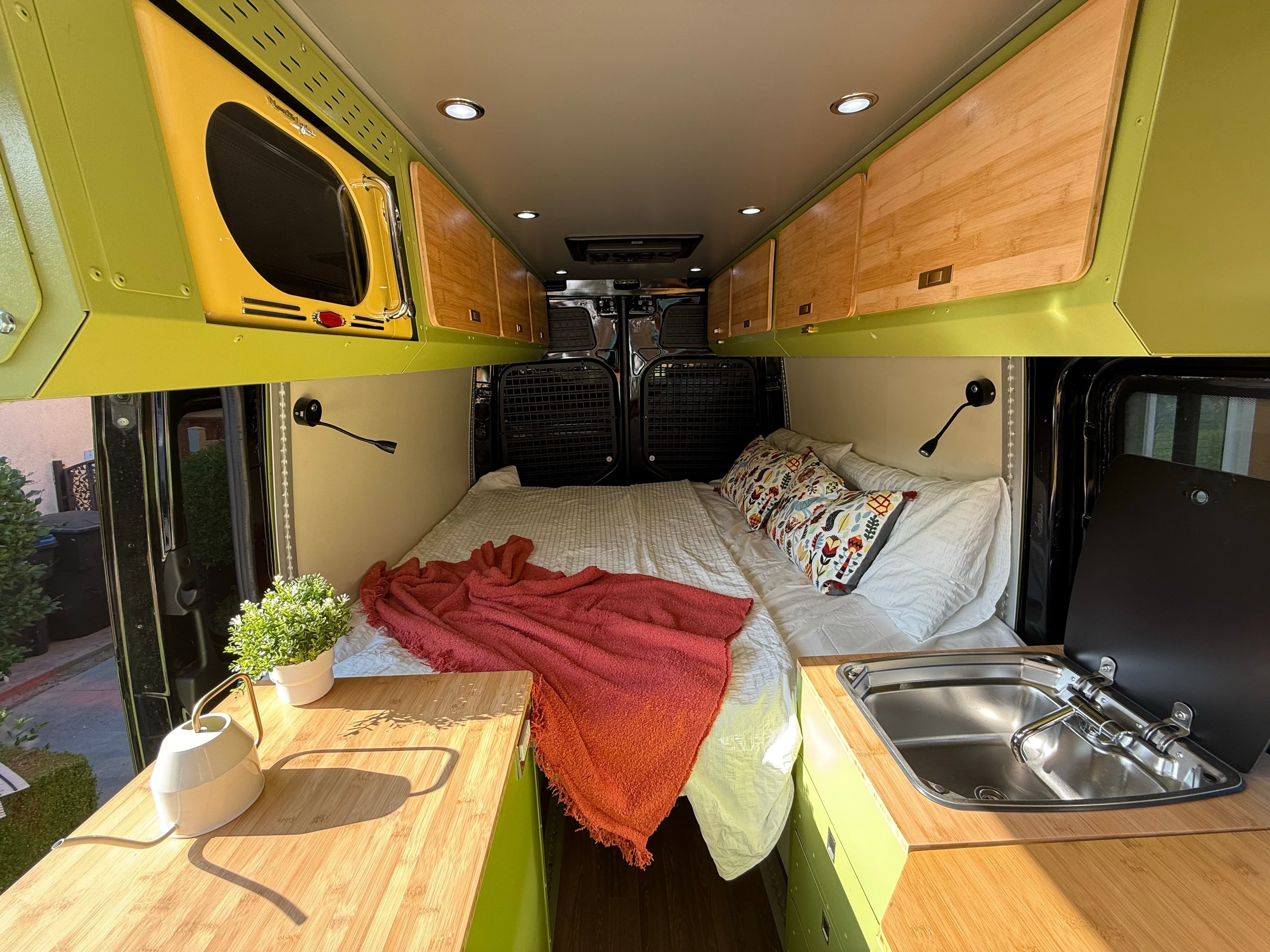 Finished camper van sleeping area, galley, and storage