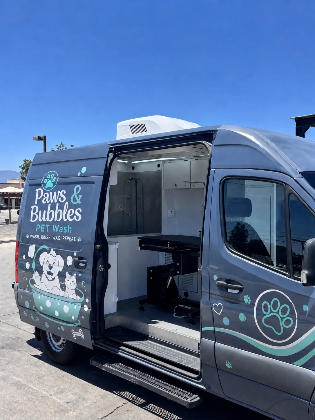 Mobile grooming van finished with an example pet-wash brand wrap, side door open to the salon